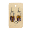 Pair of eggplant and gold earrings on a 'The Artifact House' branded card against a white background