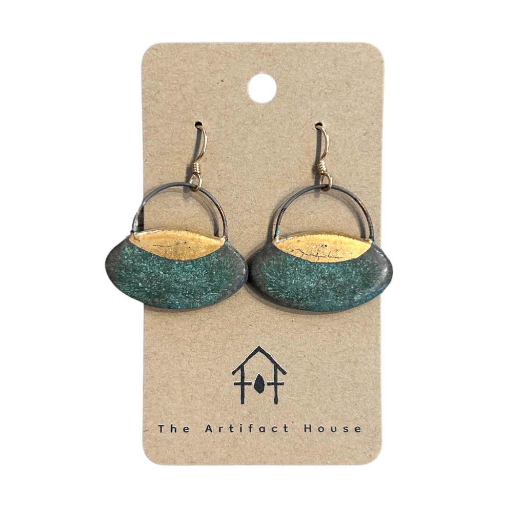 Pair of patina and gold earrings on a 'The Artifact House' branded card against a white background