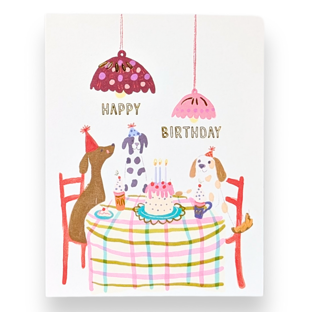 Birthday card with dogs around a table, celebrating 'Happy Birthday'.