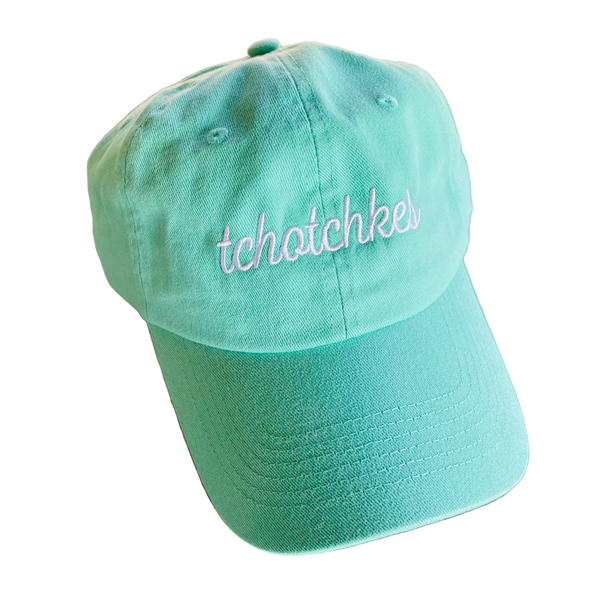 Mint green cap with 'tchatchkes' embroidery on a textured surface