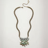 A gold-tone chain necklace featuring a statement pendant with light green rhinestones and iridescent teardrop accents, displayed on a clean white background.