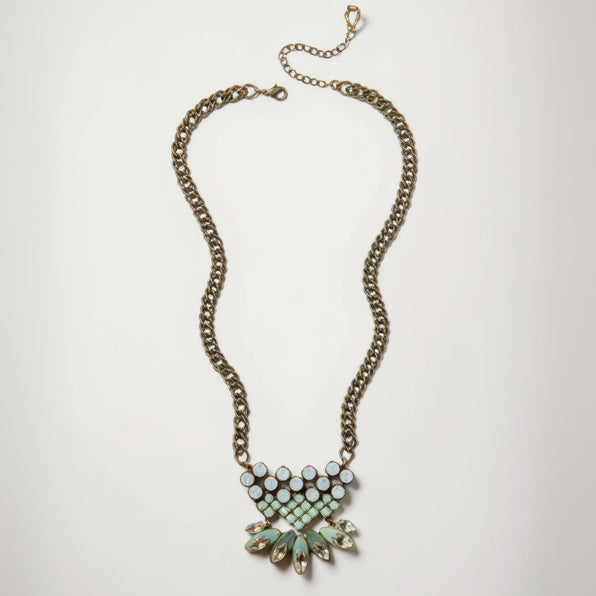 A gold-tone chain necklace featuring a statement pendant with light green rhinestones and iridescent teardrop accents, displayed on a clean white background.